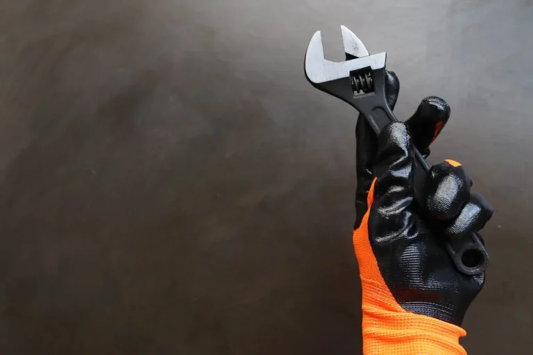 gloved hand holding wrench